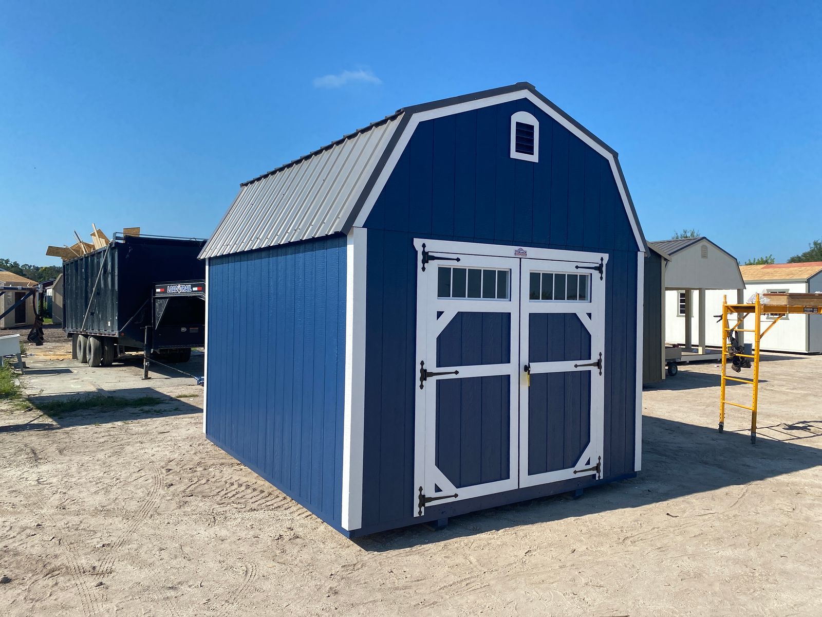 10x12 Stor-Mor Lofted Barn in Navy Blue with white trim, double shop doors with a transom window and a charcoal gambrel roof