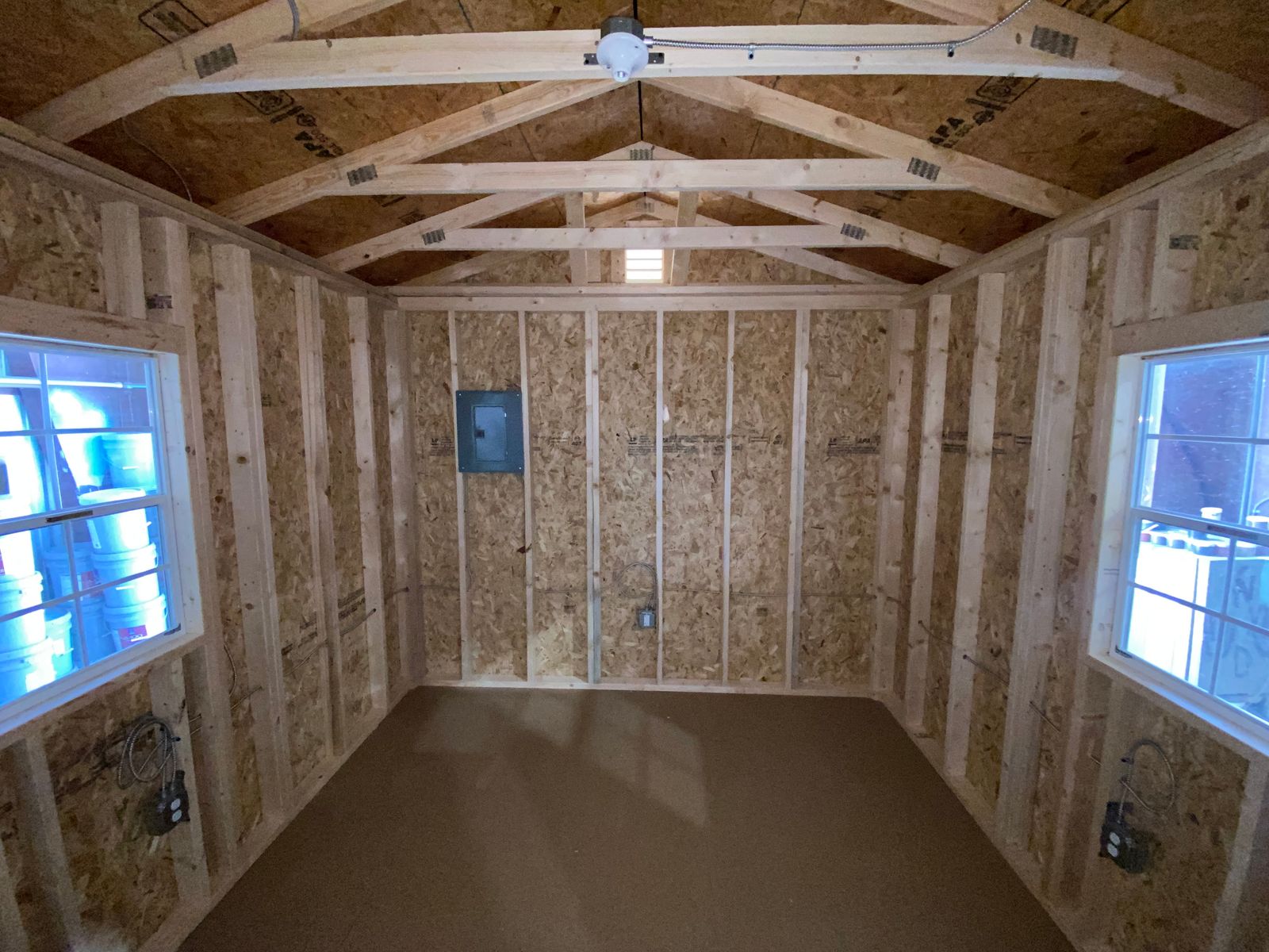 Interior of the 10x16 Navajo White cabin with two windows, an electrical panel and a ceiling light
