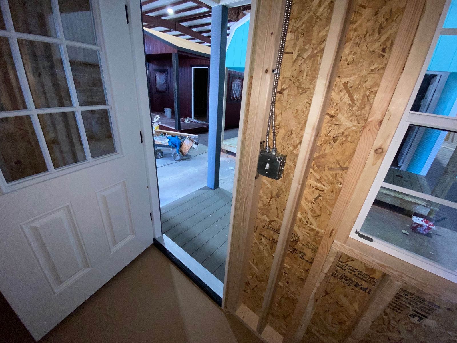 Inside the 10x16 Navajo White cabin looking out the open 9-lite door to the porch