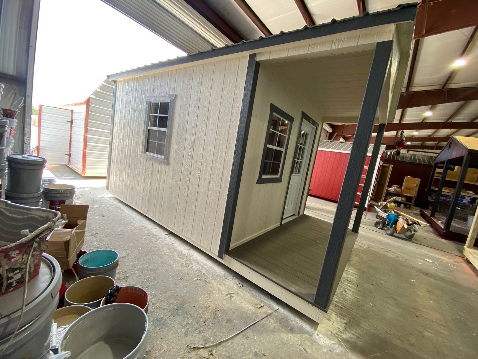 Angled side view of the 10x16 Navajo White cabin showing the porch, a window and dark gray trim