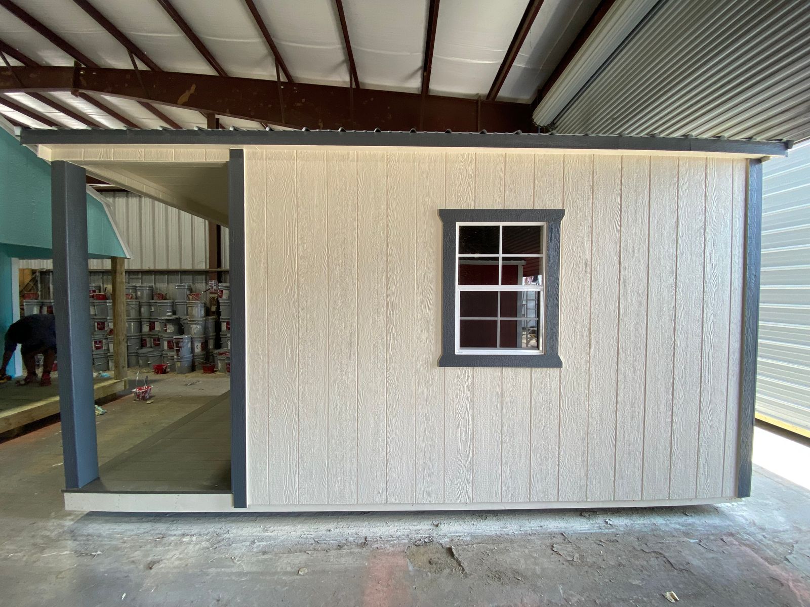 Side wall of the 10x16 Navajo White cabin with a window trimmed in dark gray and the porch at one end