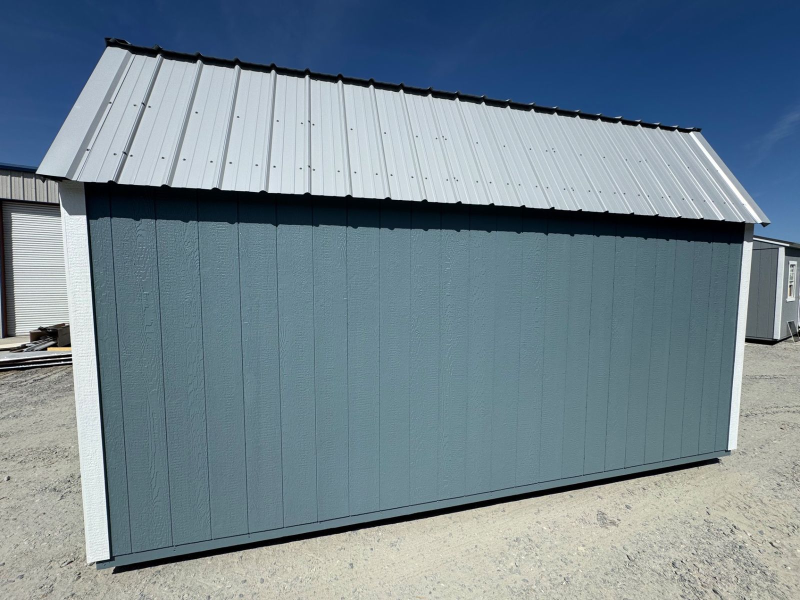 Full length of the long side wall on the 10x16 Belmont Blue Lofted Barn with white trim and gray roof