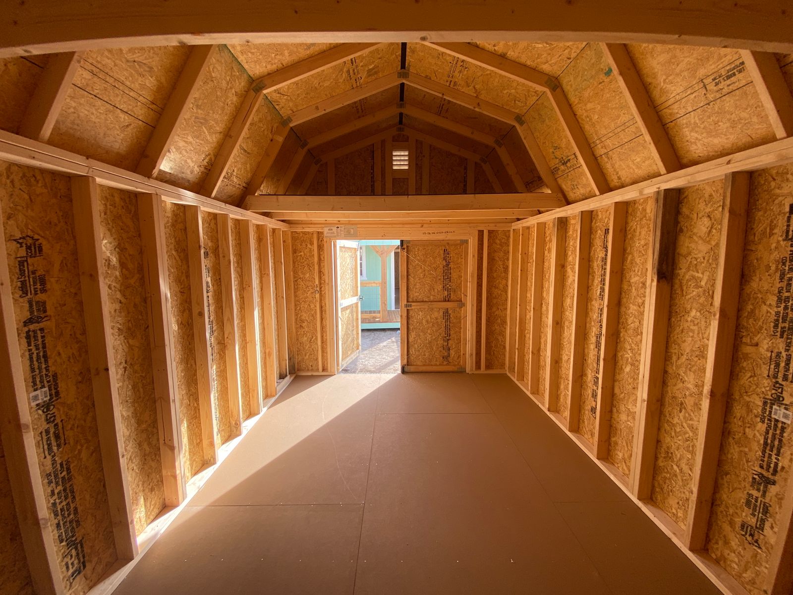 Interior of the 10x16 Buckskin Lofted Barn showing the loft framing, open wall studs and floor
