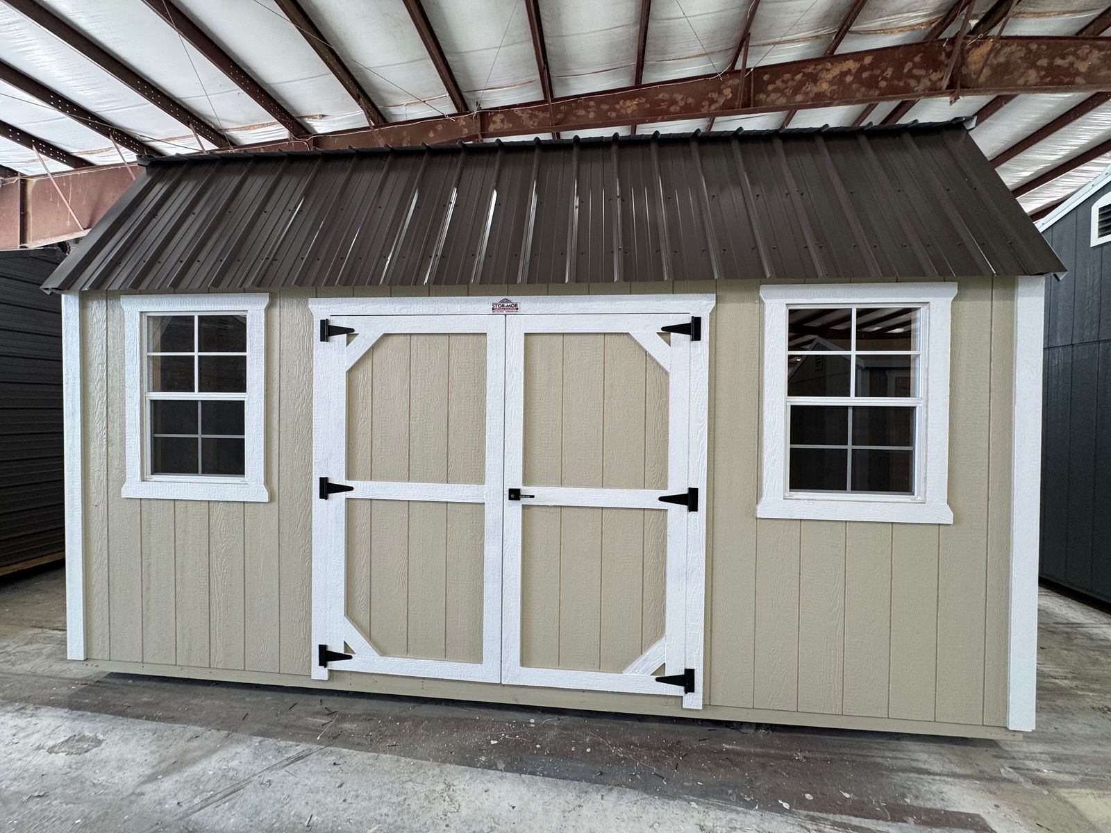 10x16 Stor-Mor Side Lofted Barn in New Holland Beige with white trim, double shop doors on the long wall and a Burnished Slate roof