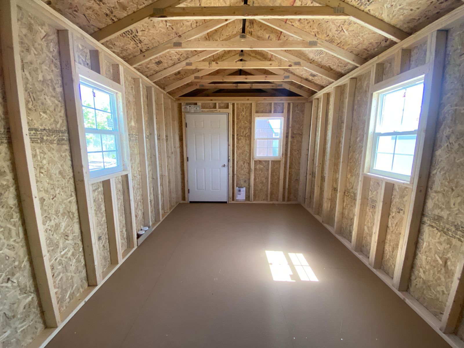 10x20 Cape Cod Gray Stor-Mor cabin interior before insulation, windows on both sides and door at far end