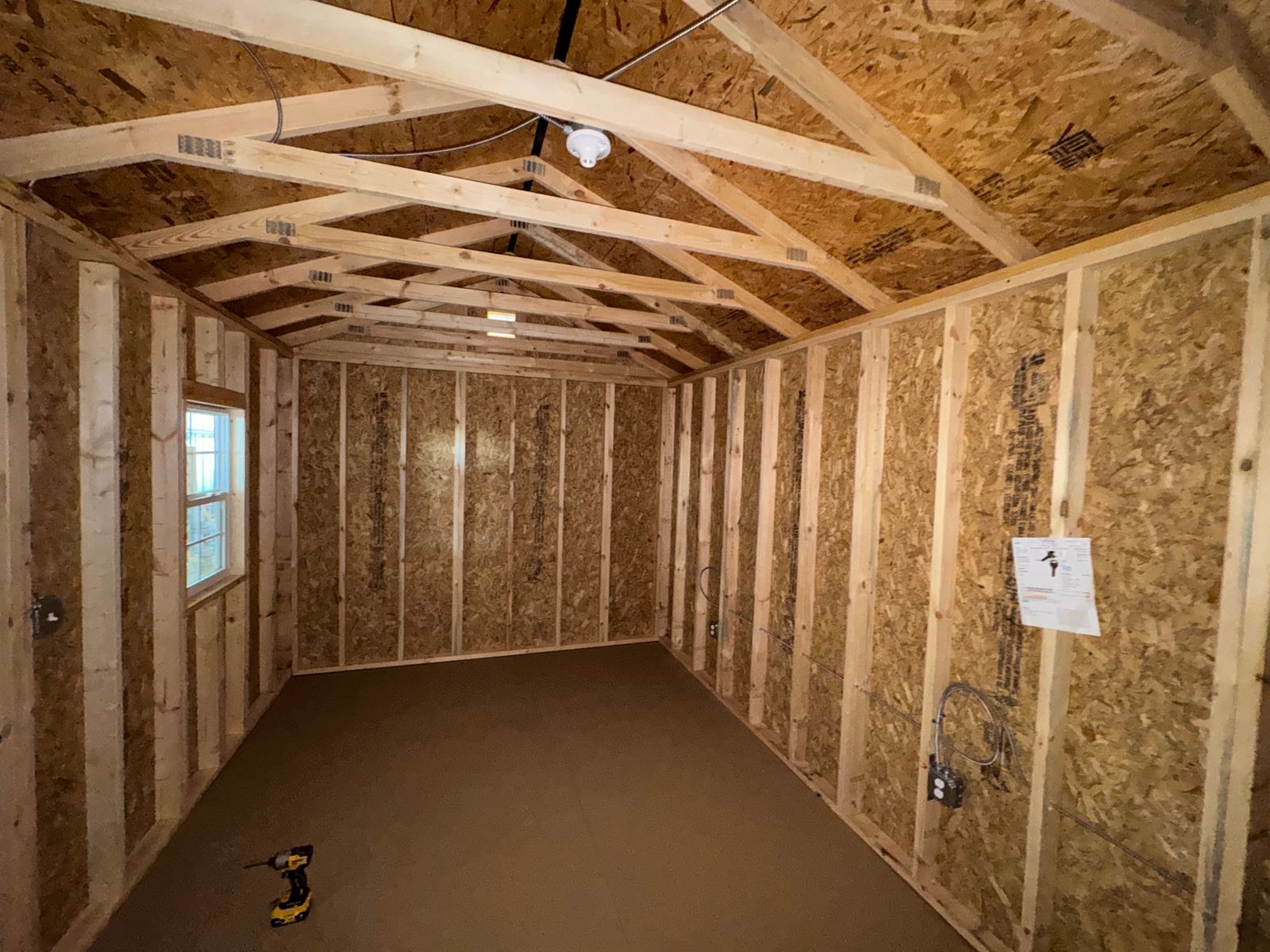 10x20 backyard office interior with open stud walls, window at far end and ceiling light