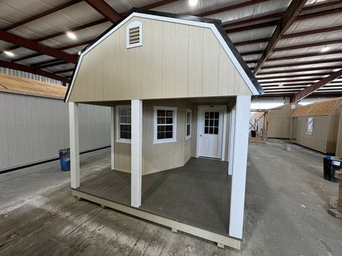 12x36 Stor-Mor Deluxe Lofted Barn Cabin in New Holland Beige with white trim, a covered front porch and a black gambrel roof