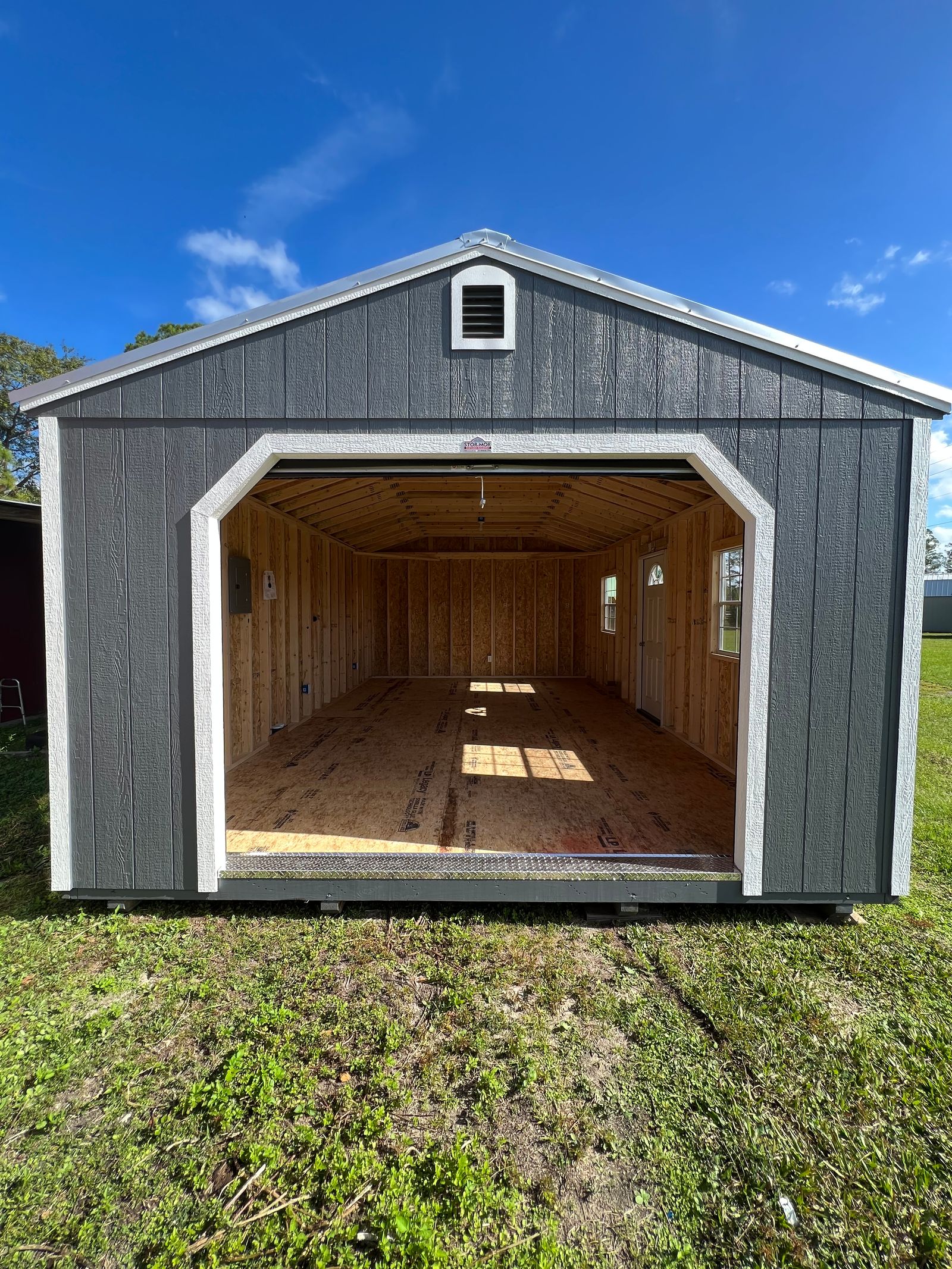14x24 Stor-Mor garage in Dark Gray with white trim, a roll-up garage door and a Galvalume metal roof