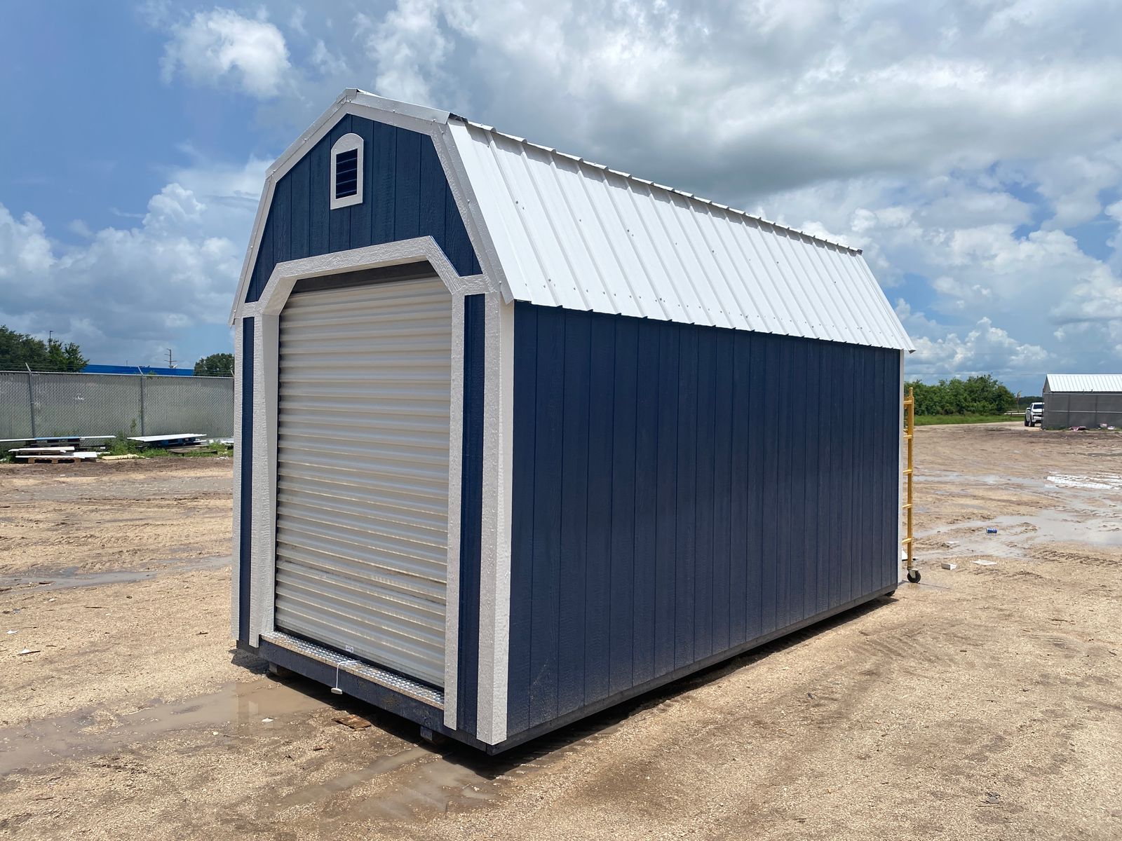8x16 Stor-Mor Lofted Barn in Navy Blue with white trim, a roll-up door and a white gambrel roof