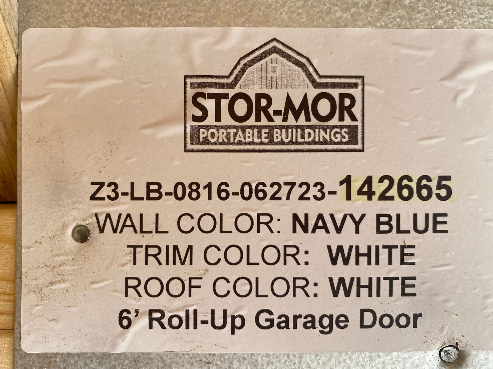 8x16 Navy Blue Lofted Barn factory color label listing white trim, white roof and a 6' roll-up garage door
